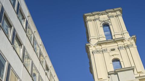 Ein Kirchturm neben einem modernen Bürogebäude