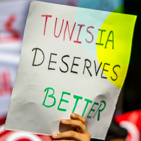 Ein Mensch hält ein Schild hoch, auf dem steht "Tunesia deserves better"