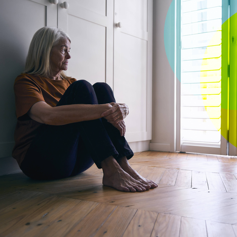 Eine Frau, die alleine auf dem Boden in einem Zimmer sitzt