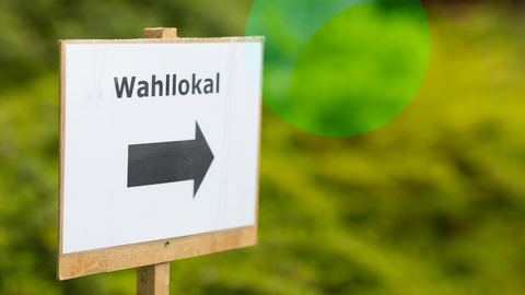 Ein Schild, auf dem Wahllokal steht. Darunter ein Pfeil, dieser Pfeil zeigt nach rechts